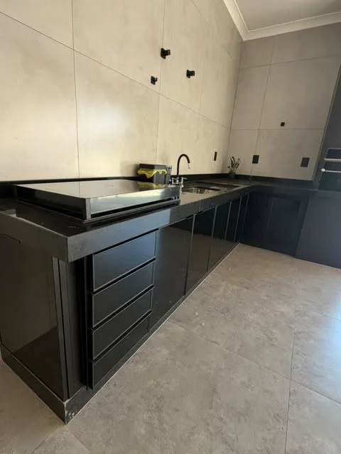 Cozinha com bancada preta e armários de portas em vidro preto com perfis de alumínio