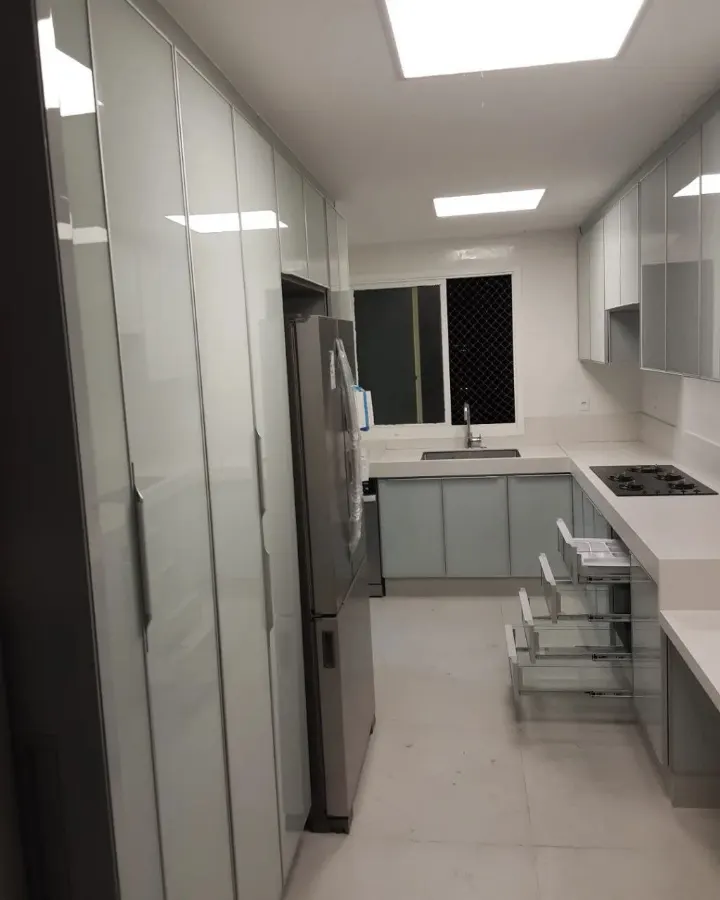 Cozinha com armários altos do piso ao teto, portas em vidro e perfis de alumínio