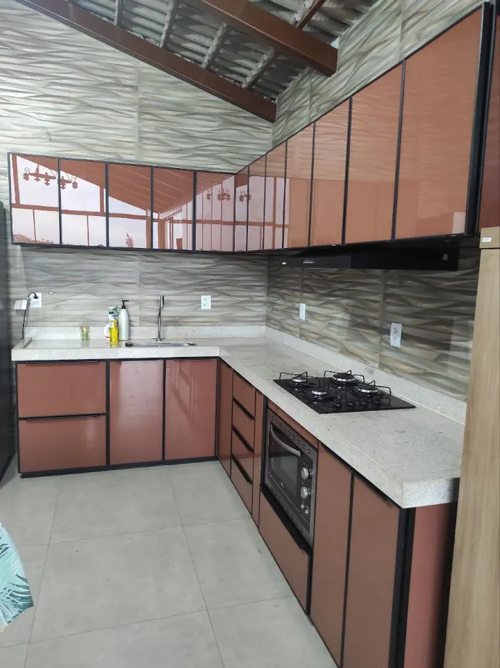 Cozinha em L com armários em vidro cor cobre e perfis de alumínio preto