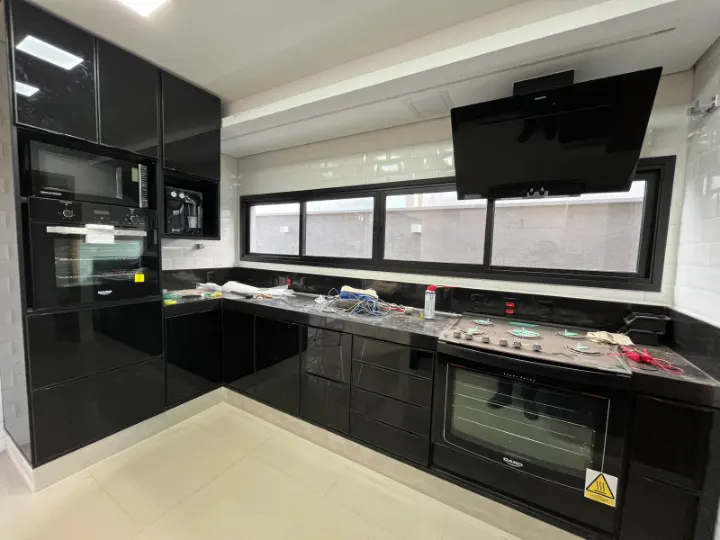 Cozinha com armários em vidro preto, forno e micro-ondas embutidos